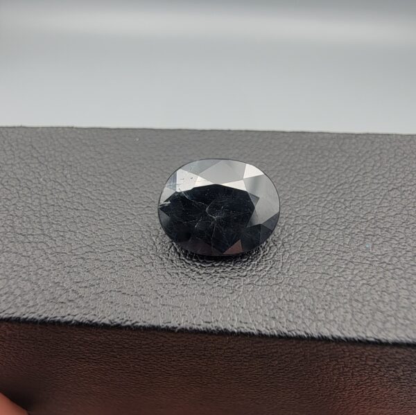 A 4.77-carat natural blue sapphire from Kanchanaburi, Thailand, featuring a classic oval faceted cut and a deep midnight blue color, displayed in a professional jeweler's box.