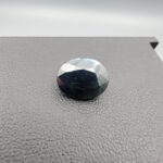 A 4.90-carat natural blue sapphire from Kanchanaburi, Thailand, featuring a classic oval faceted cut and a deep midnight blue color, displayed in a professional jeweler's box.