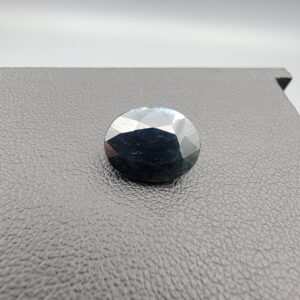 A 4.90-carat natural blue sapphire from Kanchanaburi, Thailand, featuring a classic oval faceted cut and a deep midnight blue color, displayed in a professional jeweler's box.