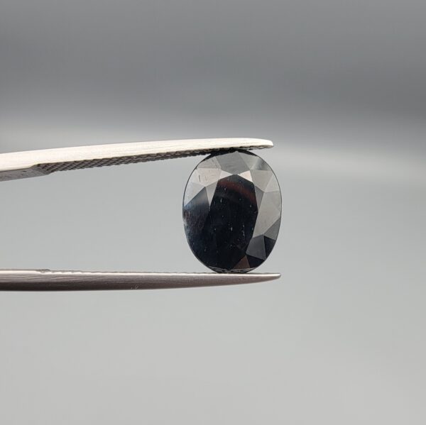 A 4.90-carat natural blue sapphire from Kanchanaburi, Thailand, featuring a classic oval faceted cut and a deep midnight blue color, displayed in a professional jeweler's box.
