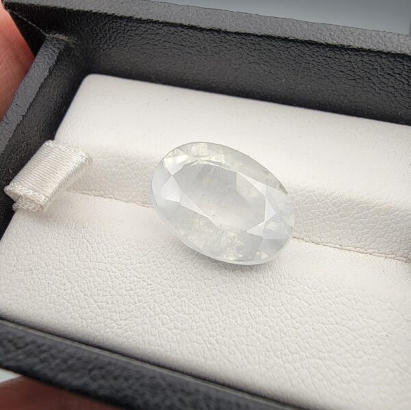 A massive 14.78-carat natural white sapphire from Sri Lanka, featuring a brilliant colorless clarity and masterful faceted cut, presented in a luxury jeweler's display box.