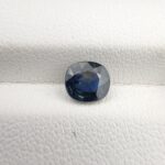 ​A 1.28-carat natural teal blue sapphire from Kanchanaburi, Thailand, with an oval faceted cut and a saturated blue-green color, presented in a professional white jeweler's box.