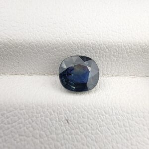 ​A 1.28-carat natural teal blue sapphire from Kanchanaburi, Thailand, with an oval faceted cut and a saturated blue-green color, presented in a professional white jeweler's box.