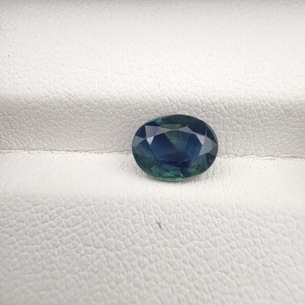 A large 2.06-carat natural teal blue sapphire from Kanchanaburi, Thailand, featuring a masterfully faceted oval cut and deep blue-green saturation, shown in a professional white jeweler's box.