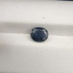 A 1.76-carat natural blue sapphire from Kanchanaburi, Thailand, featuring an oval faceted cut and deep royal blue saturation, presented in a professional jeweler's box.
