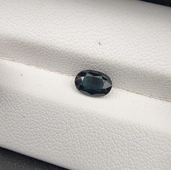 A 1.01-carat natural blue sapphire from Kanchanaburi, Thailand, featuring a masterfully faceted oval cut and deep royal blue color, presented in a professional white jeweler's box.