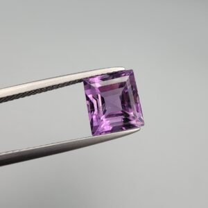 A natural 3.72-carat Brazilian amethyst (Katela) with a bright purple saturation and a sharp square faceted cut, held in professional jeweler's tweezers against a neutral background.