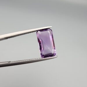 ​A natural 3.72-carat Brazilian amethyst (Katela) with a bright purple saturation and a sharp rectangle faceted cut, held in professional jeweler's tweezers.