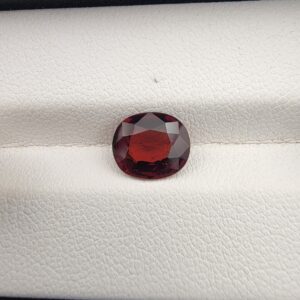 A natural 2.14-carat Red Garnet from Madagascar with a deep red sparkle and a polished oval faceted cut, resting on a white textured surface as shown in file 20260512_205905.jpg.