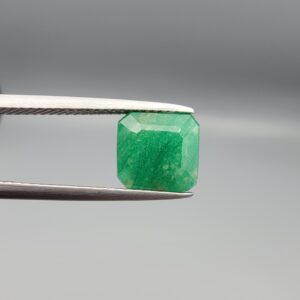 A natural 2.85-carat green emerald from the Swat Valley, Pakistan, featuring an octagon step cut and soft green saturation, held in professional jeweler's tweezers.