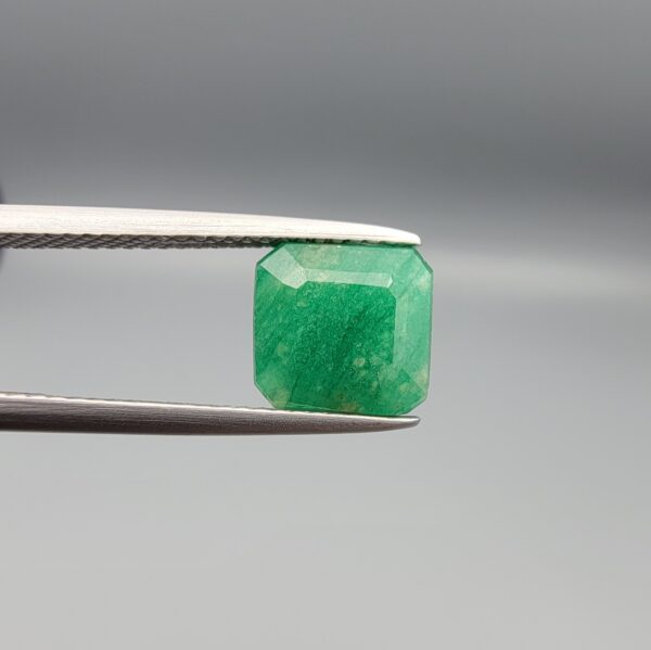 A natural 2.85-carat green emerald from the Swat Valley, Pakistan, featuring an octagon step cut and soft green saturation, held in professional jeweler's tweezers.