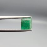 A natural 1.00-carat green emerald from the Swat Valley, Pakistan, featuring an octagon step cut and rich green saturation with visible internal natural inclusions, held in professional jeweler's tweezers.