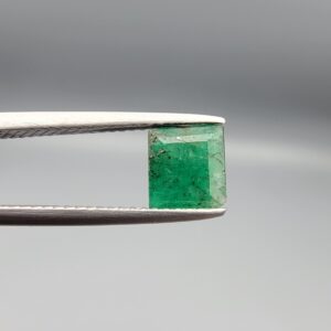 A natural 1.00-carat green emerald from the Swat Valley, Pakistan, featuring an octagon step cut and rich green saturation with visible internal natural inclusions, held in professional jeweler's tweezers.