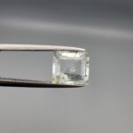 A natural 2.28-carat pale blue aquamarine from Shigar Valley, Pakistan, featuring an octagon step cut with visible natural internal veining and inclusions, held in professional jeweler's tweezers.