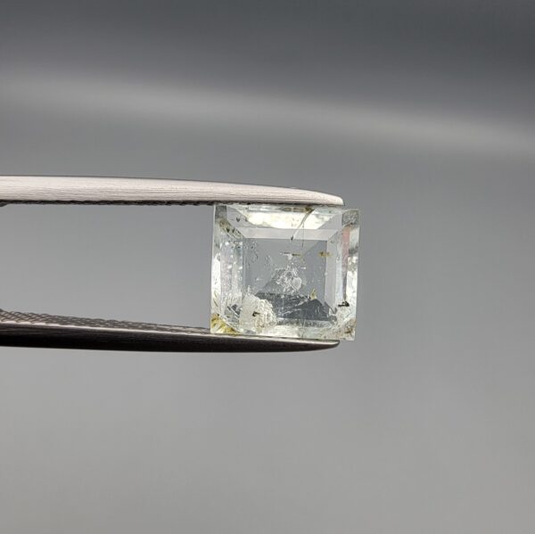 A natural 2.28-carat pale blue aquamarine from Shigar Valley, Pakistan, featuring an octagon step cut with visible natural internal veining and inclusions, held in professional jeweler's tweezers.