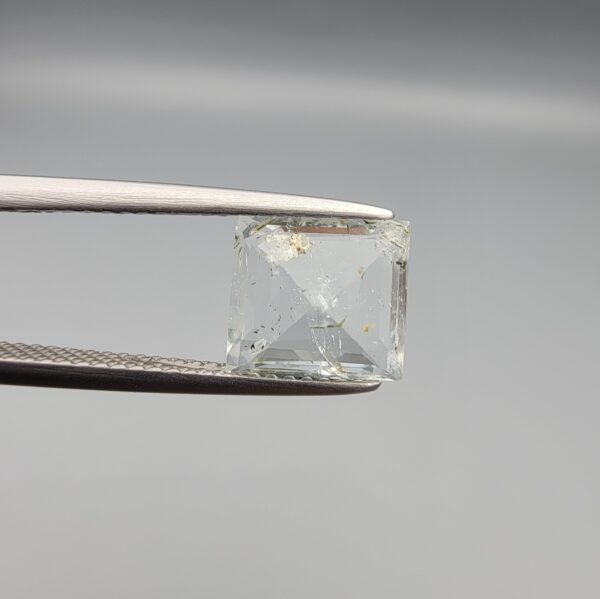A natural 2.28-carat pale blue aquamarine from Shigar Valley, Pakistan, featuring an octagon step cut with visible natural internal veining and inclusions, held in professional jeweler's tweezers.