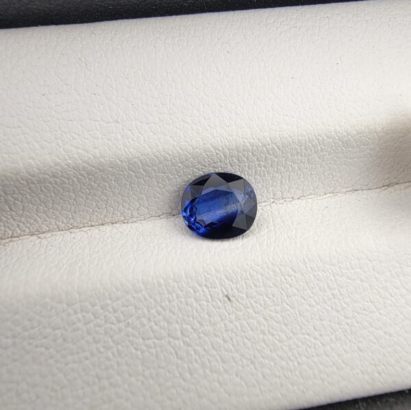 A natural 1.00-carat blue sapphire (Neelam) from Ceylon, Sri Lanka, featuring a faceted oval cut with a distinct cornflower blue saturation, held in professional jeweler's tweezers.