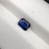 A natural 0.96-carat blue sapphire (Neelam) from Ceylon, Sri Lanka, featuring a faceted oval cut with rich cornflower blue color and high clarity, held securely in professional jeweler's tweezers.