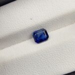 A natural 1.00-carat blue sapphire (Neelam) from Ceylon, Sri Lanka, featuring a faceted oval cut with a classic cornflower blue saturation and exceptional clarity, held in professional jeweler's tweezers.