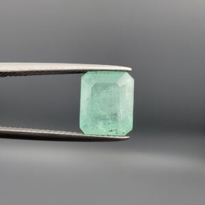 A natural 4.00-carat green emerald from the Chitral Valley, Pakistan, featuring a well-proportioned octagon step cut and classic green saturation with natural internal inclusions, held securely in professional jeweler's tweezers.