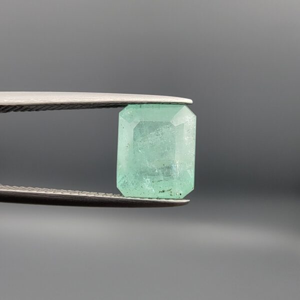 A natural 4.00-carat green emerald from the Chitral Valley, Pakistan, featuring a well-proportioned octagon step cut and classic green saturation with natural internal inclusions, held securely in professional jeweler's tweezers.