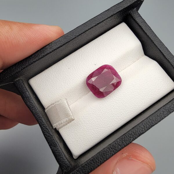 ​An exceptionally large and rare 8.12-carat natural red ruby from Mozambique featuring a premium faceted cushion cut with rich red color saturation and natural internal characteristics, held in professional jeweler's tweezers.