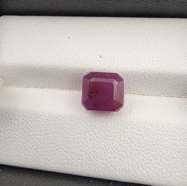 A rare and substantial 5.24-carat purplish-red natural ruby (Yaqoot) from Mozambique, showcasing a premium octagonal step cut with parallel facet lines and a beautiful translucent crystal body, resting on a textured white background.