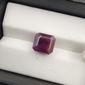An exceptionally large and rare 7.91-carat purplish-red natural ruby (Yaqoot) from Mozambique, showcasing a premium octagonal step cut with sharp parallel facet lines and a beautiful translucent crystal body, resting on a textured white background.