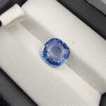 A premium 3.85-carat natural Ceylon blue sapphire gemstone displaying an elegant cushion cut with excellent symmetry and a deep royal blue color profile, resting inside a textured white leather jewelry box liner.