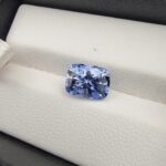 ​A premium 3.67-carat natural Ceylon blue sapphire gemstone displaying an elegant cushion cut with excellent symmetry and a deep royal blue color profile, resting inside a textured white leather jewelry box liner.