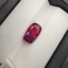 A premium 4.02-carat natural Mozambique ruby gemstone held horizontally by jeweler's tweezers, showcasing an elegant elongated cushion cut, vibrant purplish-red body color, and stunning transparent clarity with distinct internal crystal inclusions.