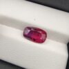 A premium 4.02-carat natural Mozambique ruby gemstone held horizontally by jeweler's tweezers, showcasing an elegant elongated cushion cut, vibrant purplish-red body color, and stunning transparent clarity with distinct internal crystal inclusions.