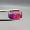 A premium 4.02-carat natural Mozambique ruby gemstone held horizontally by jeweler's tweezers, showcasing an elegant elongated cushion cut, vibrant purplish-red body color, and stunning transparent clarity with distinct internal crystal inclusions.