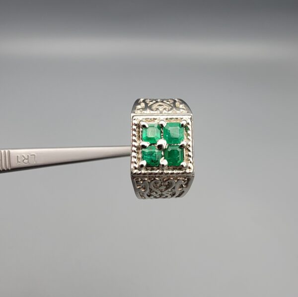 ​A handcrafted men's 925 sterling silver ring showcasing a vertical channel layout of 4 natural Swat Valley emeralds with a rich alpine green color profile, displayed from multiple professional angles on a reflective surface.