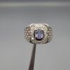 ​A premium men's 925 sterling silver statement ring featuring an oval-cut natural Ceylon blue sapphire centerpiece surrounded by a brilliant double border of sparkling white zircons, displayed from multiple professional angles on a reflective surface.