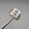 ​A premium men's 925 sterling silver statement ring featuring an oval-cut natural Ceylon blue sapphire centerpiece surrounded by a brilliant double border of sparkling white zircons, displayed from multiple professional angles on a reflective surface.
