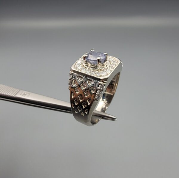 ​A premium men's 925 sterling silver statement ring featuring an oval-cut natural Ceylon blue sapphire centerpiece surrounded by a brilliant double border of sparkling white zircons, displayed from multiple professional angles on a reflective surface.