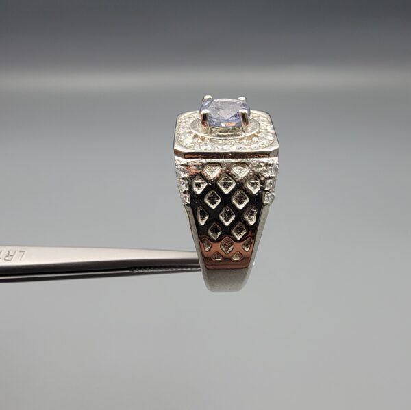 ​A premium men's 925 sterling silver statement ring featuring an oval-cut natural Ceylon blue sapphire centerpiece surrounded by a brilliant double border of sparkling white zircons, displayed from multiple professional angles on a reflective surface.