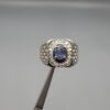 ​A premium men's 925 sterling silver statement ring featuring an oval-cut natural Ceylon blue sapphire centerpiece surrounded by a brilliant double border of sparkling white zircons, displayed from multiple professional angles on a reflective surface.