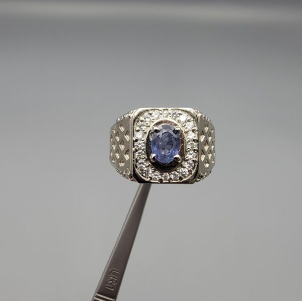 ​A premium men's 925 sterling silver statement ring featuring an oval-cut natural Ceylon blue sapphire centerpiece surrounded by a brilliant double border of sparkling white zircons, displayed from multiple professional angles on a reflective surface.