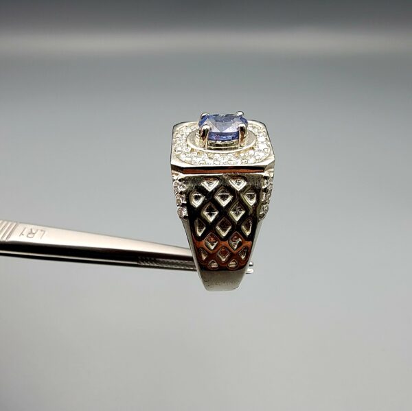 ​A premium men's 925 sterling silver statement ring featuring an oval-cut natural Ceylon blue sapphire centerpiece surrounded by a brilliant double border of sparkling white zircons, displayed from multiple professional angles on a reflective surface.