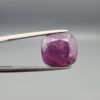 ​A massive 9.65-carat natural, unheated Ceylon purple sapphire (Khooni Neelam) showing a premium faceted cushion mixed cut, displaying a rich purple body color with mysterious undertones, resting inside a textured white leather jewelry box liner.