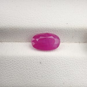 ​A premium 2.61-carat natural, unheated Afghan ruby from Kabul (Jegdalek) with a faceted oval cut, displaying a vibrant pinkish-red translucent color profile held securely in professional jeweler's tweezers.
