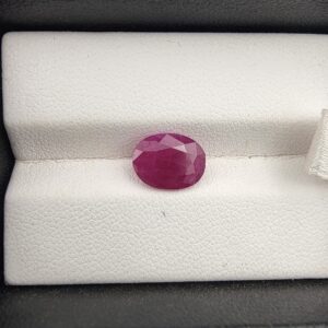 A premium 2.97-carat natural, unheated Mozambican ruby showing a faceted oval cut with a rich translucent red body color, held securely in professional jeweler's tweezers.