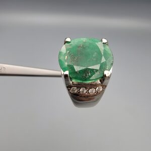 ​A custom men's statement ring featuring a massive oval-cut natural green Swat Valley emerald with distinctive sparkling metallic pyrite inclusions inside, set in highly polished 925 sterling silver accented with rows of round artificial zircons on the sides.