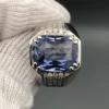 A luxury men's 925 sterling silver statement ring featuring a massive 11.80-carat oval-cut natural Ceylon blue sapphire surrounded by a brilliant halo of 0.47 carats of white diamonds, resting inside a textured white leather jewelry box liner.