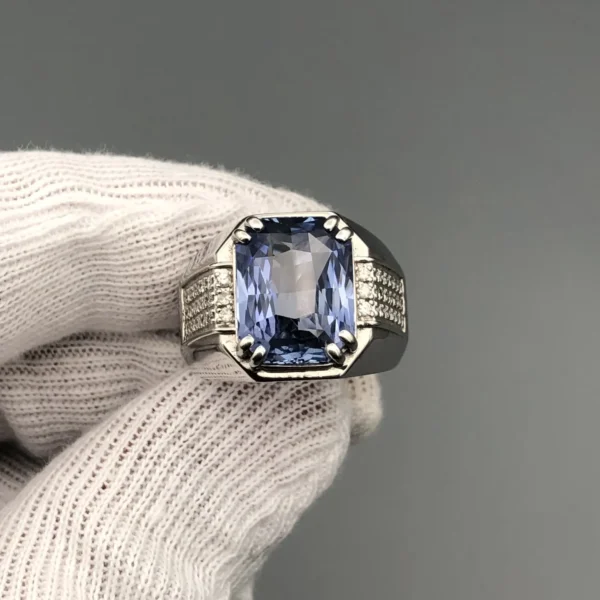 A luxury men's 925 sterling silver statement ring featuring a massive 11.80-carat oval-cut natural Ceylon blue sapphire surrounded by a brilliant halo of 0.47 carats of white diamonds, resting inside a textured white leather jewelry box liner.