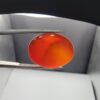 ​A premium 19.17-carat natural oval Yemeni carnelian agate cabochon held in tweezers. While appearing dark brown in flat shadow, strong backlighting transforms it into a brilliant, translucent fiery orange gemstone displaying elegant, natural curved agate zoning lines.