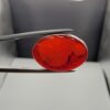 ​A premium 14.26-carat natural oval Yemeni carnelian agate cabochon held in tweezers. While appearing dark brown with a dense core in flat shadow, strong backlighting transforms it into a brilliant, translucent fiery orange gemstone displaying elegant, natural dendritic cloud-like agate zoning patterns along its lower and side edges.