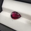 ​A premium 3.51-carat natural Mozambique Rubellite Tourmaline gemstone resting elegantly on a white textured leather insert inside a black presentation box. The loose, earth-mined corundum alternative is precision faceted into a beautifully proportioned pear shape, exhibiting a deeply saturated magenta-red body color with rich wine-red flashes reflecting from its teardrop crown.